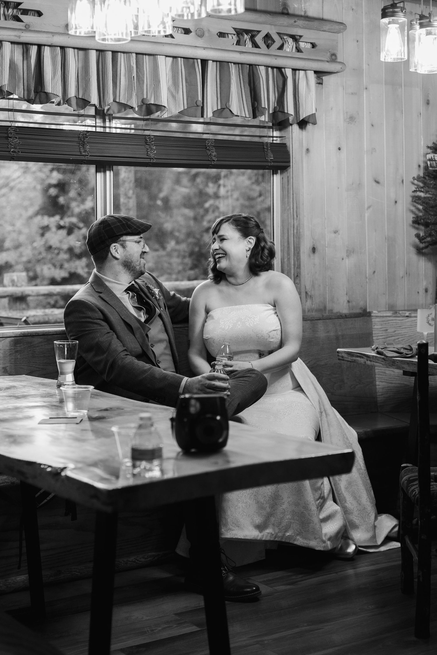 Black and white photo series of a couple sitting at a rustic wooden table in casual conversation.