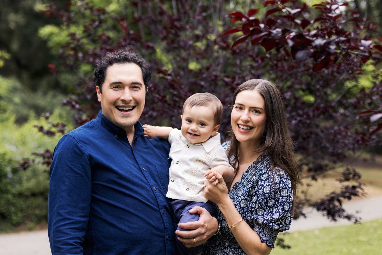 Family photoshoot in a garden with purple foliage creating a beautiful natural backdrop.