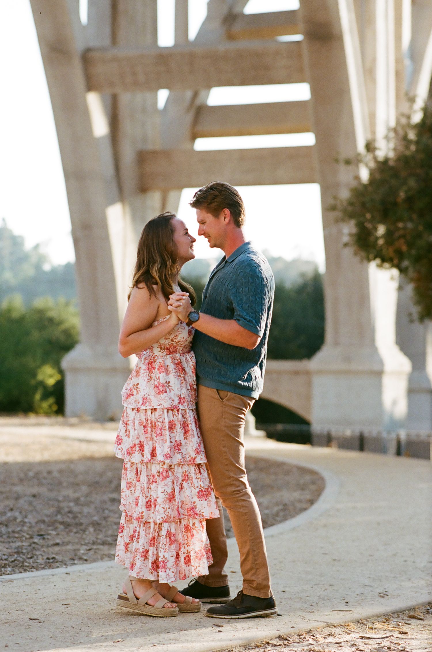 A couple shares an intimate dance moment under architectural columns in natural lighting.