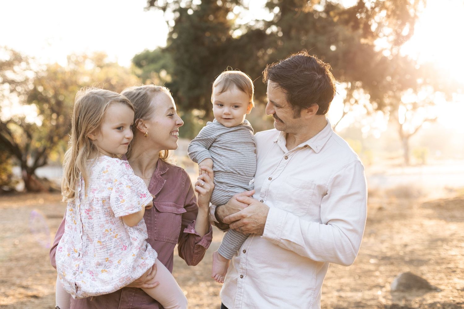 Family enjoying a warm sunset photoshoot outdoors in casual attire.