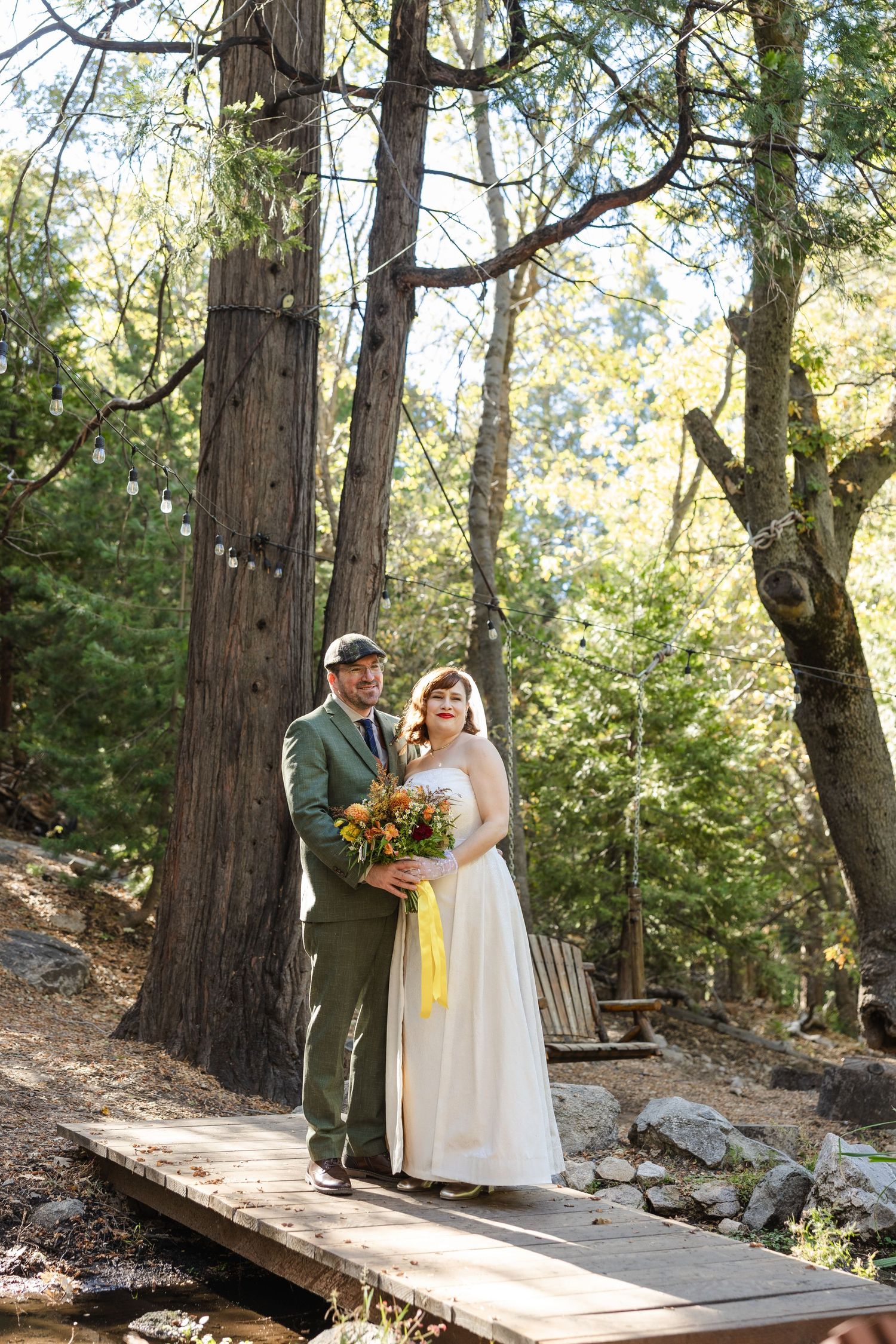 Wedding couple posing on wooden walkway in forest setting.