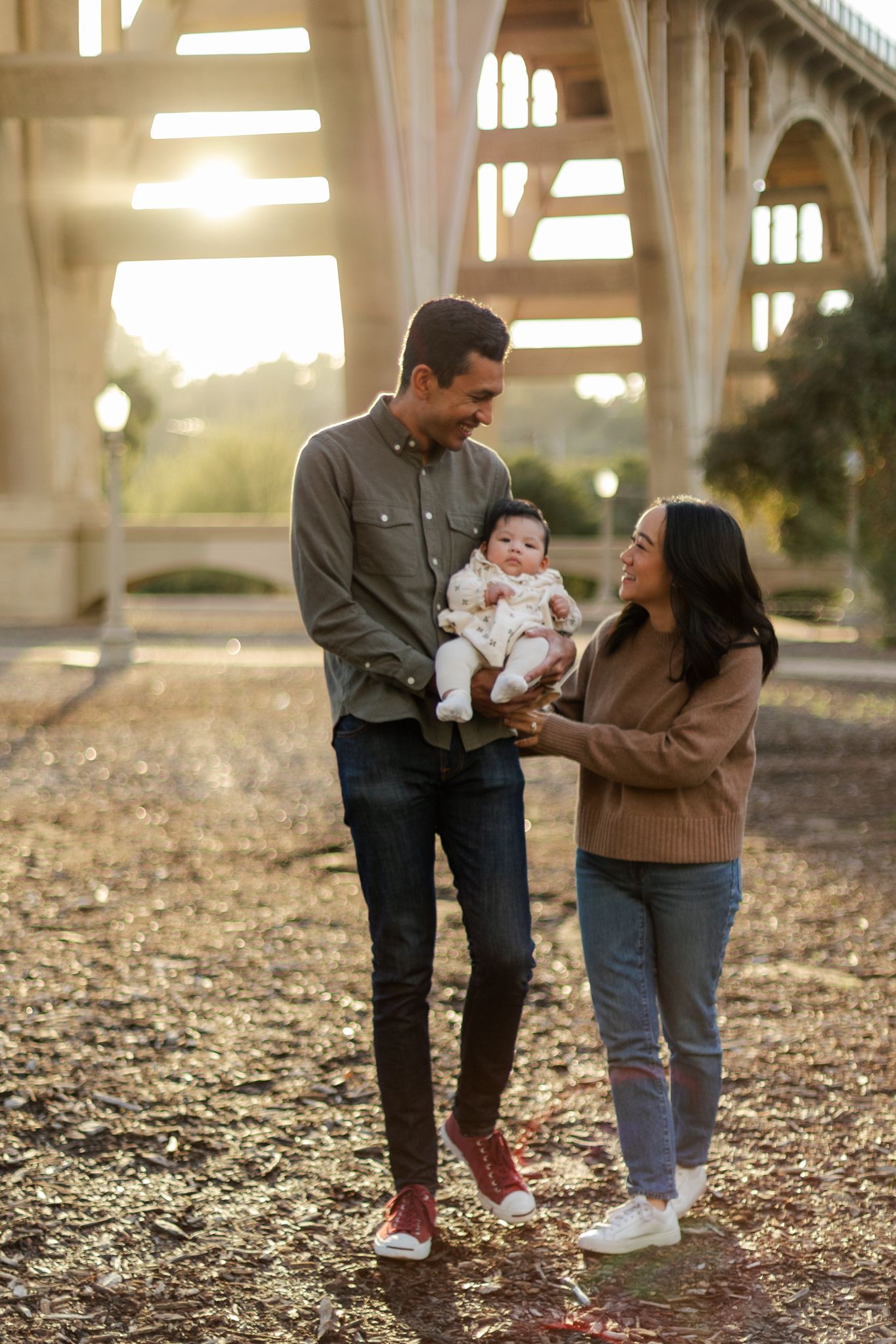 Family walking together on fallen leaves during golden hour in an outdoor setting.
