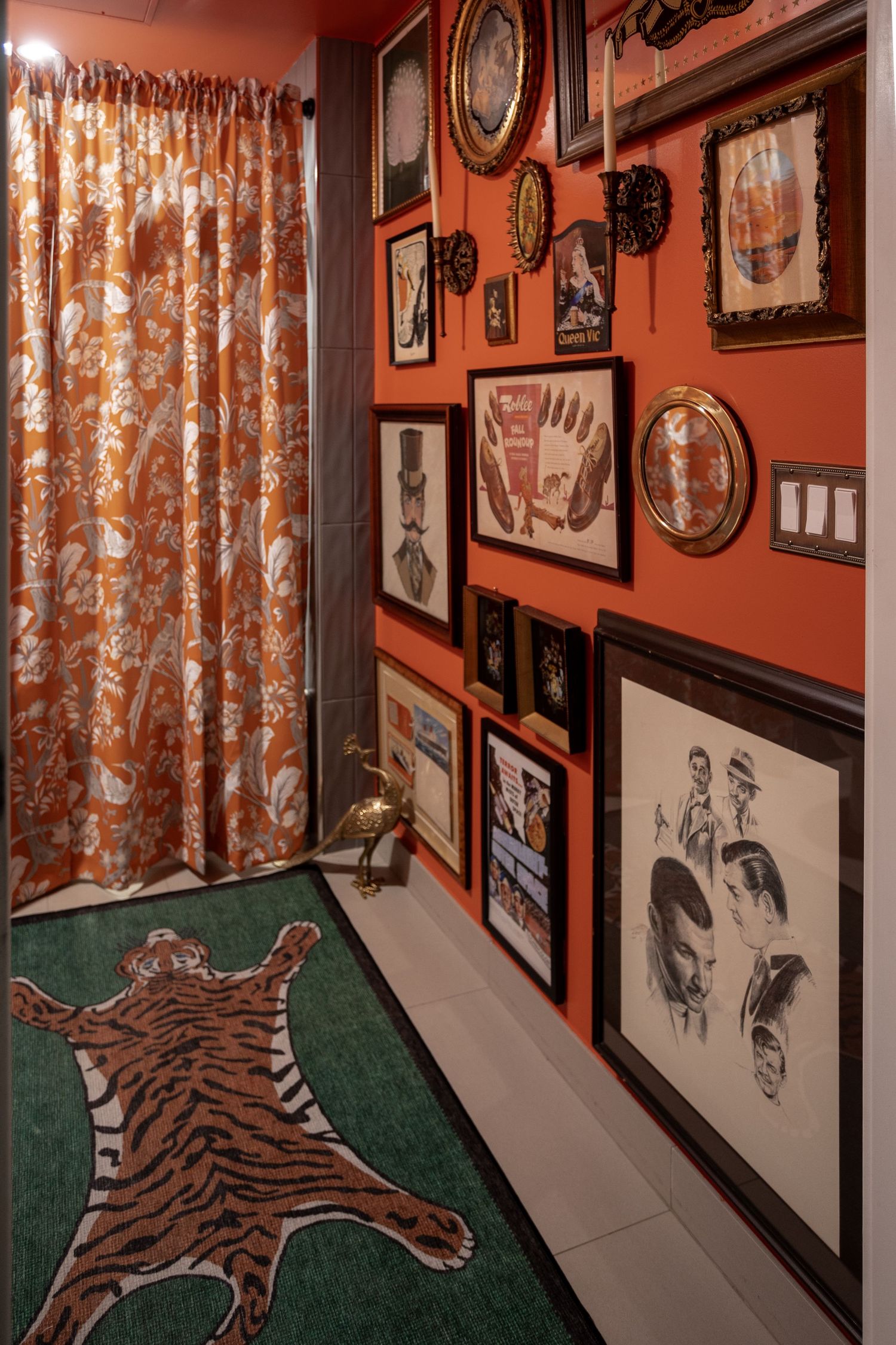 Eclectic hallway with orange walls, gallery art display, tiger rug, floral curtains, and green carpet runner.