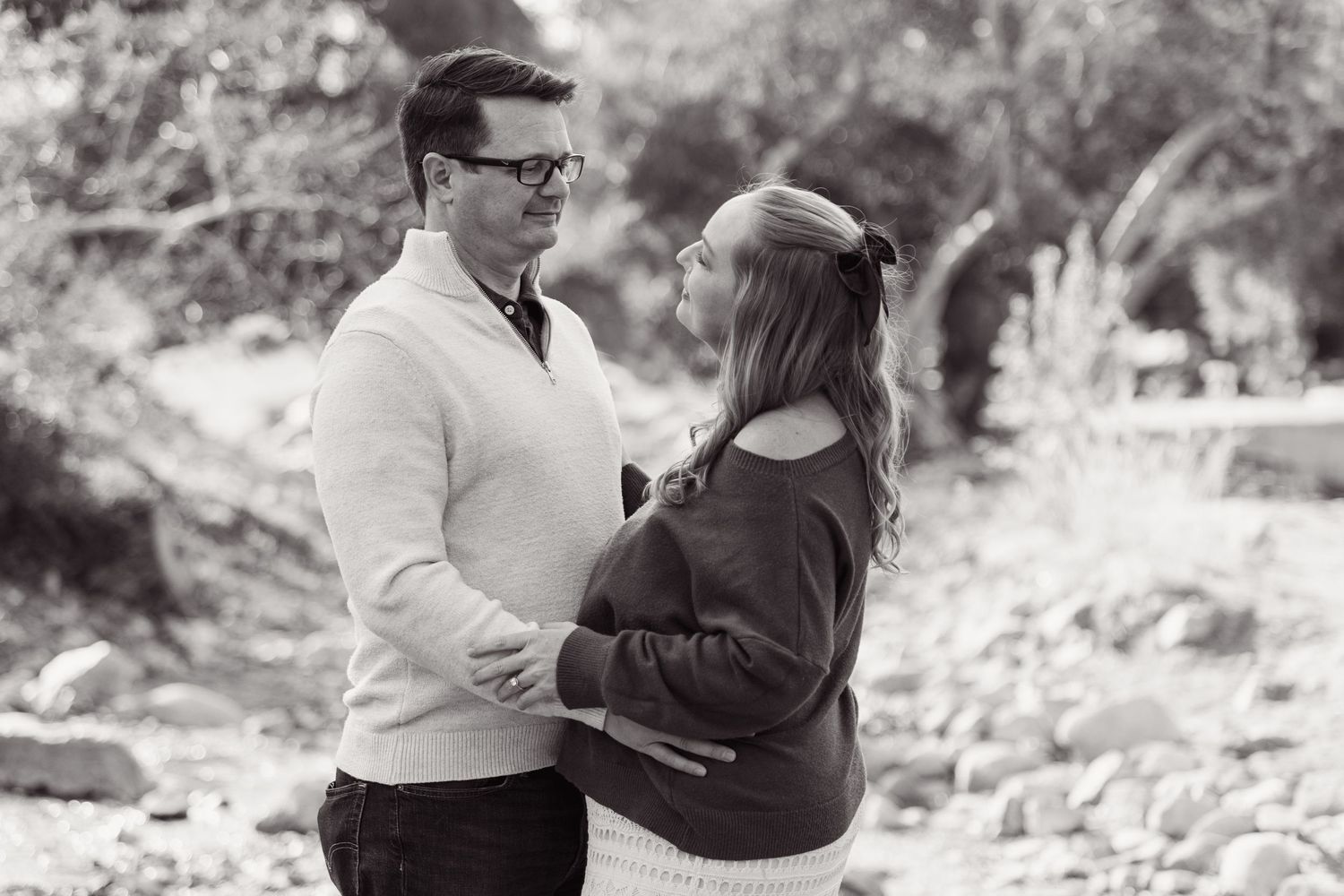 A couple in black and white embraces during an outdoor winter photoshoot.