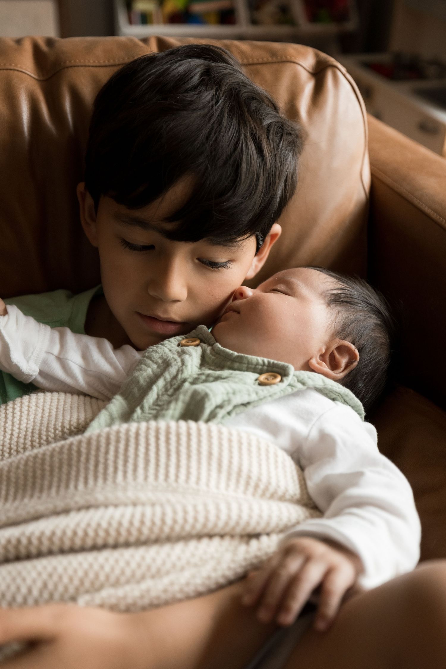 Intimate lifestyle newborn photography session on brown leather couch.