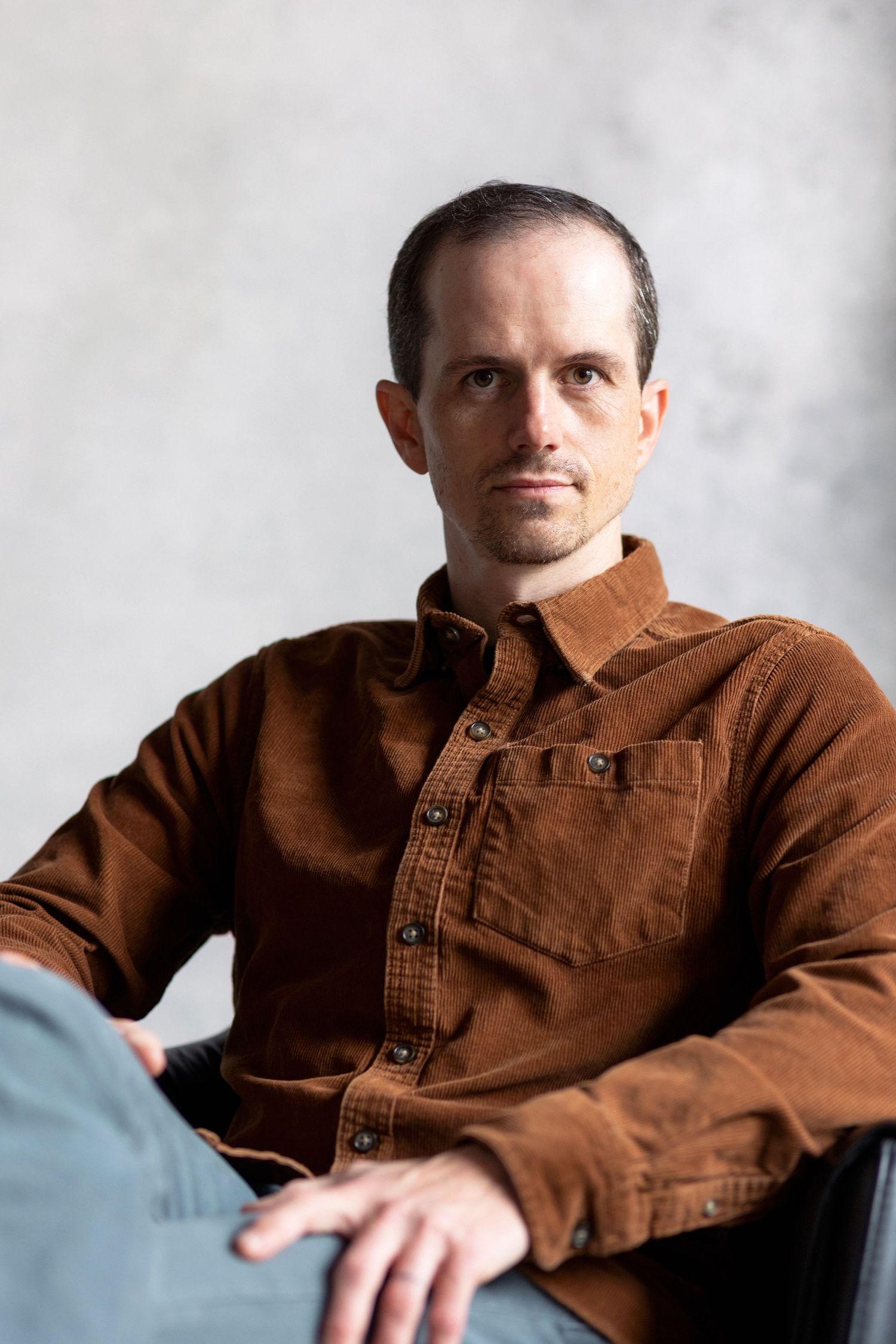 Person wearing brown corduroy jacket shown in multiple seated poses.