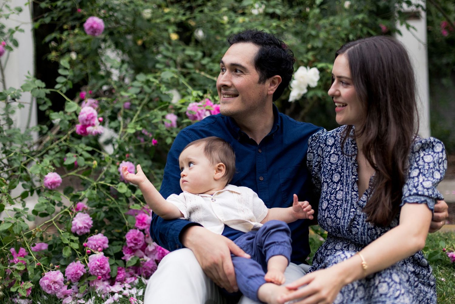 Family enjoying time together in a garden with vibrant pink roses.