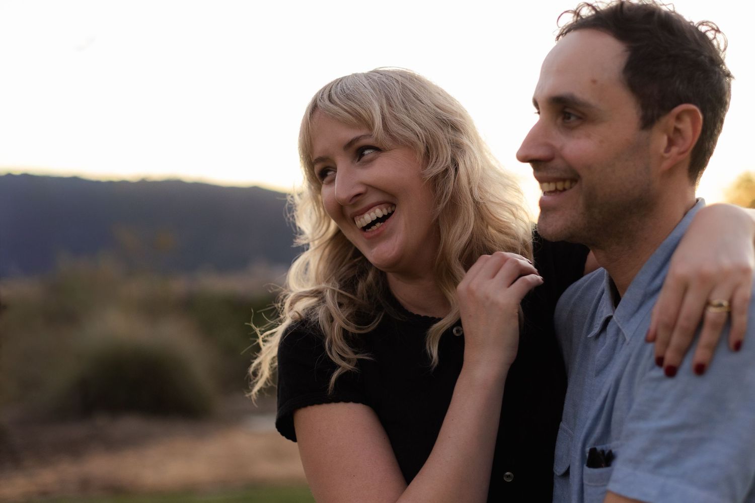 Couple sharing intimate moments during sunset in a natural outdoor setting.
