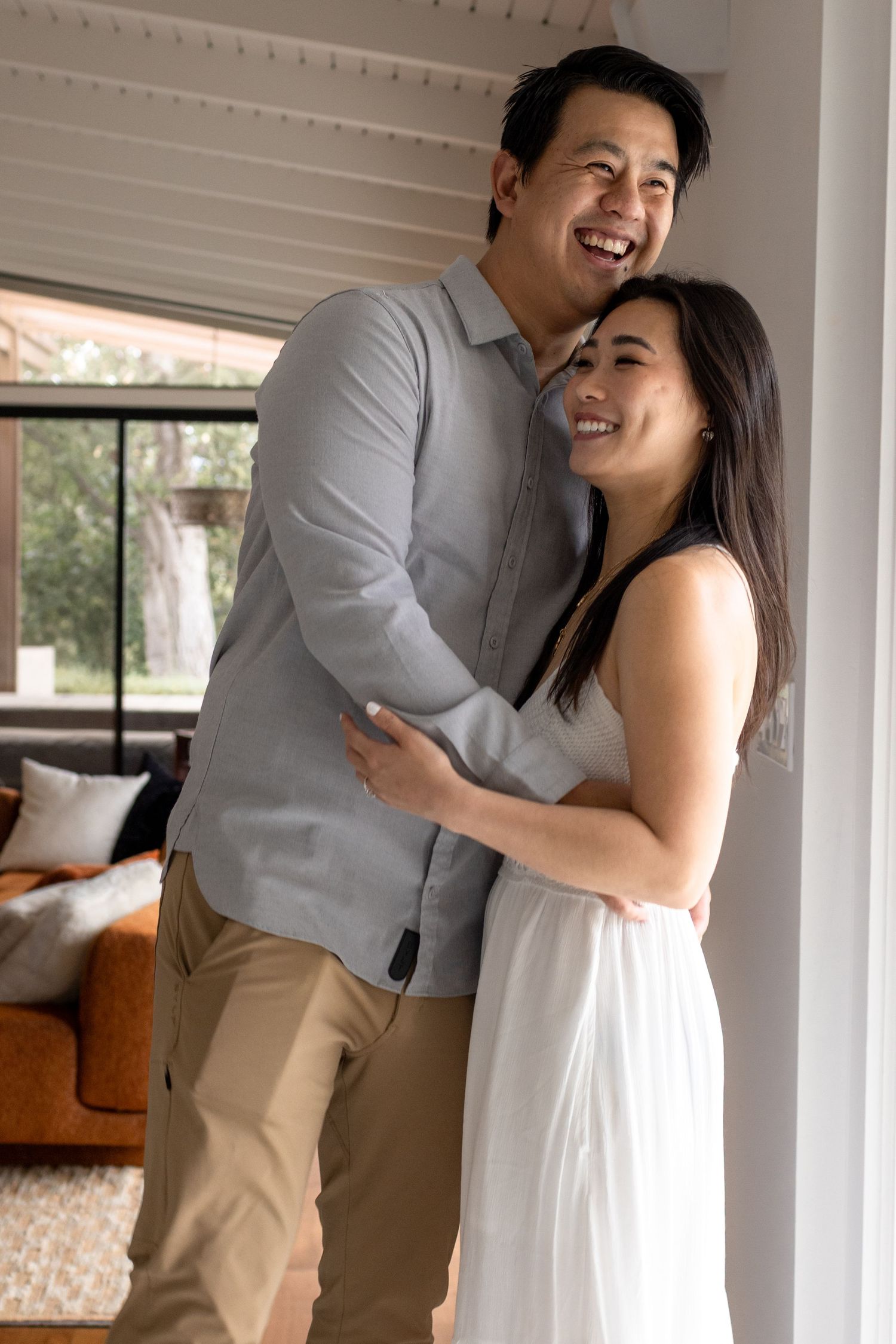 Joyful couple laughing and embracing in bright indoor setting.