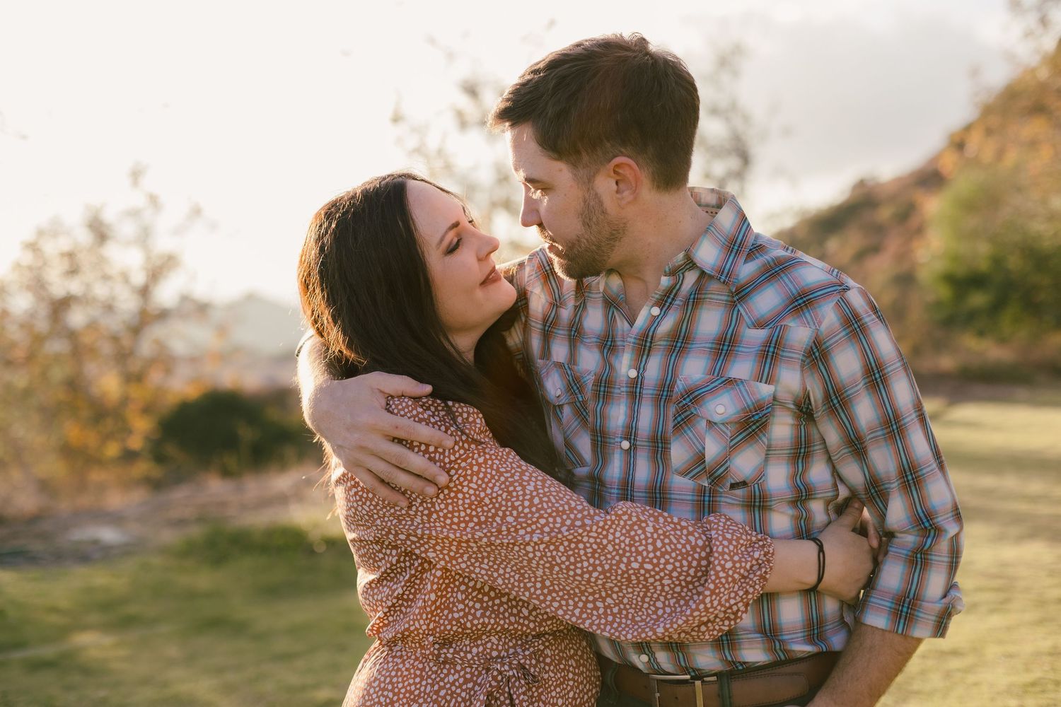 Romantic sunset engagement photos with couple embracing in golden light.