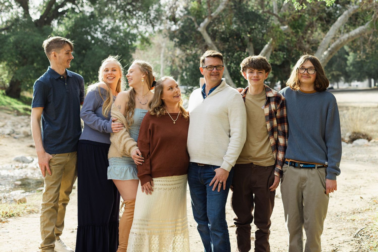 Large family group poses casually together in an outdoor natural setting.