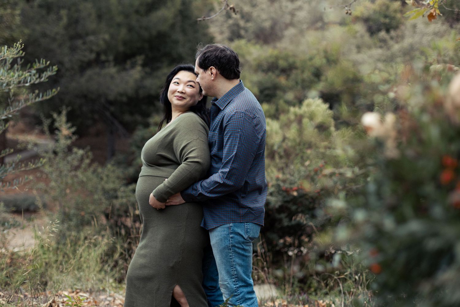 Candid maternity photography session captured outdoors among rocks and autumn foliage.