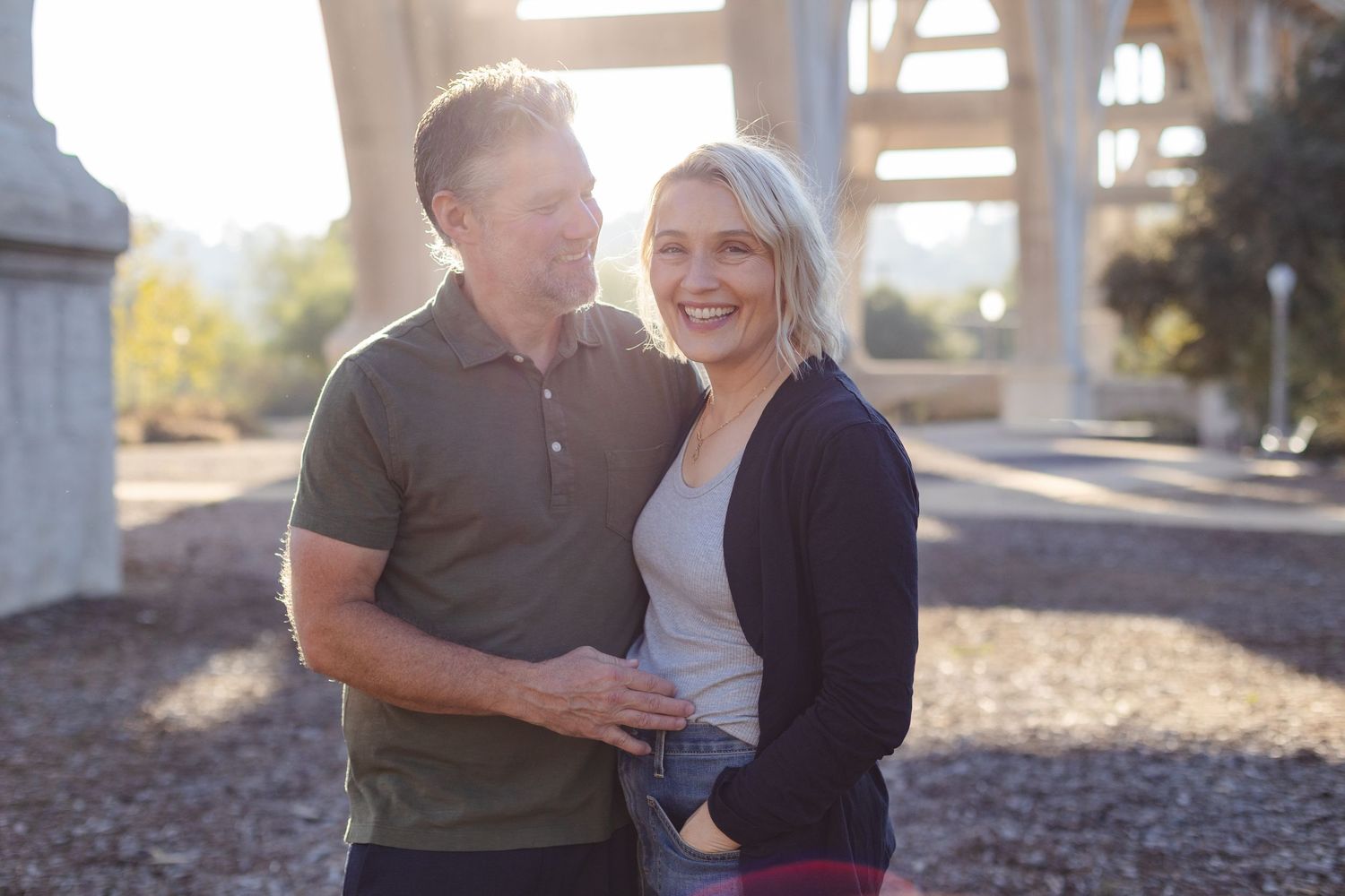 A joyful couple sharing a laugh while embracing under an outdoor structure.