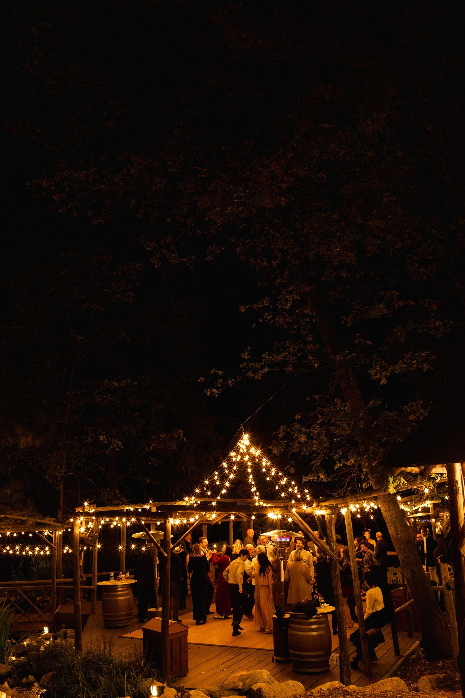 Evening outdoor venue decorated with twinkling string lights hanging between trees.