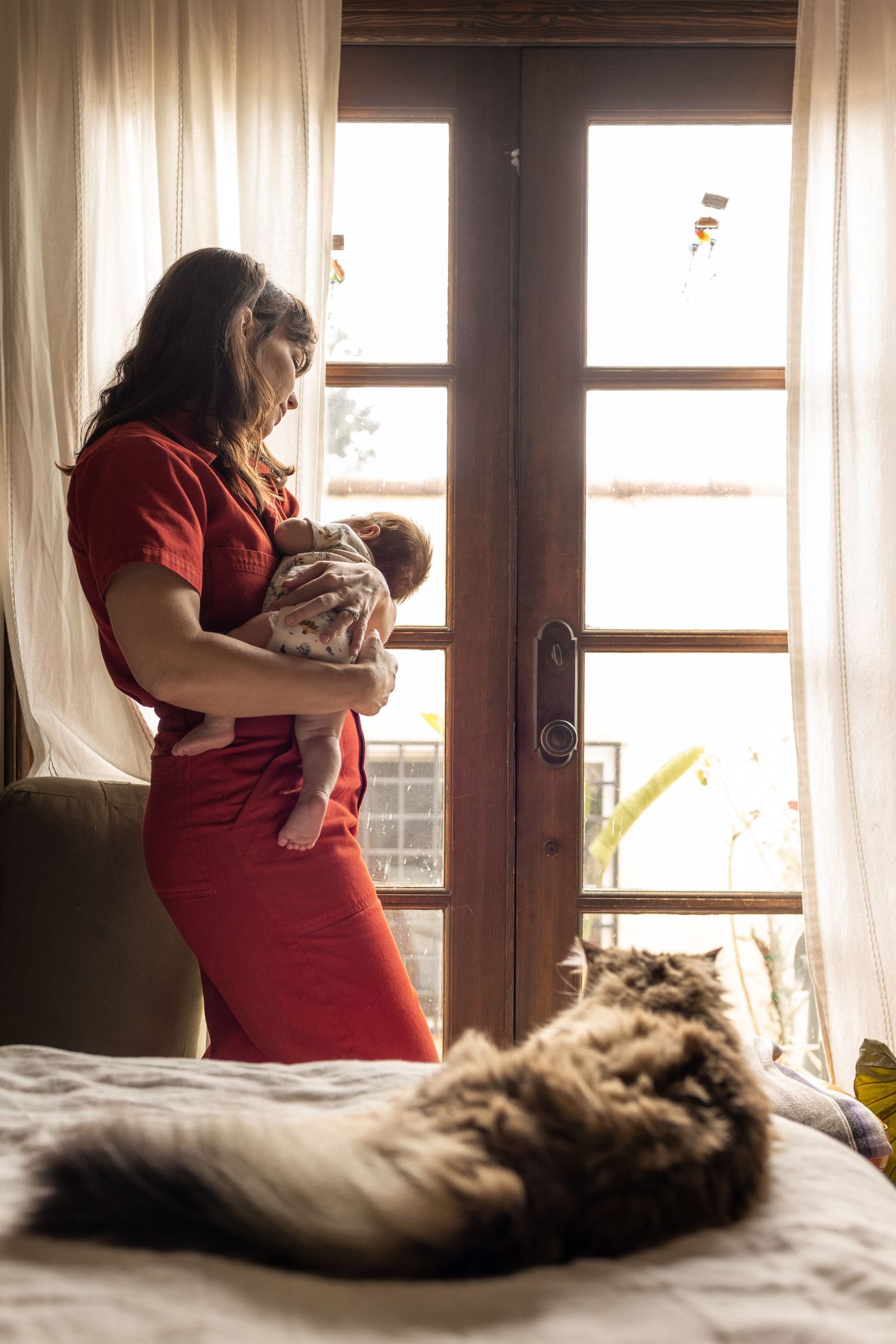 Intimate newborn photography session by a window with natural light streaming in.