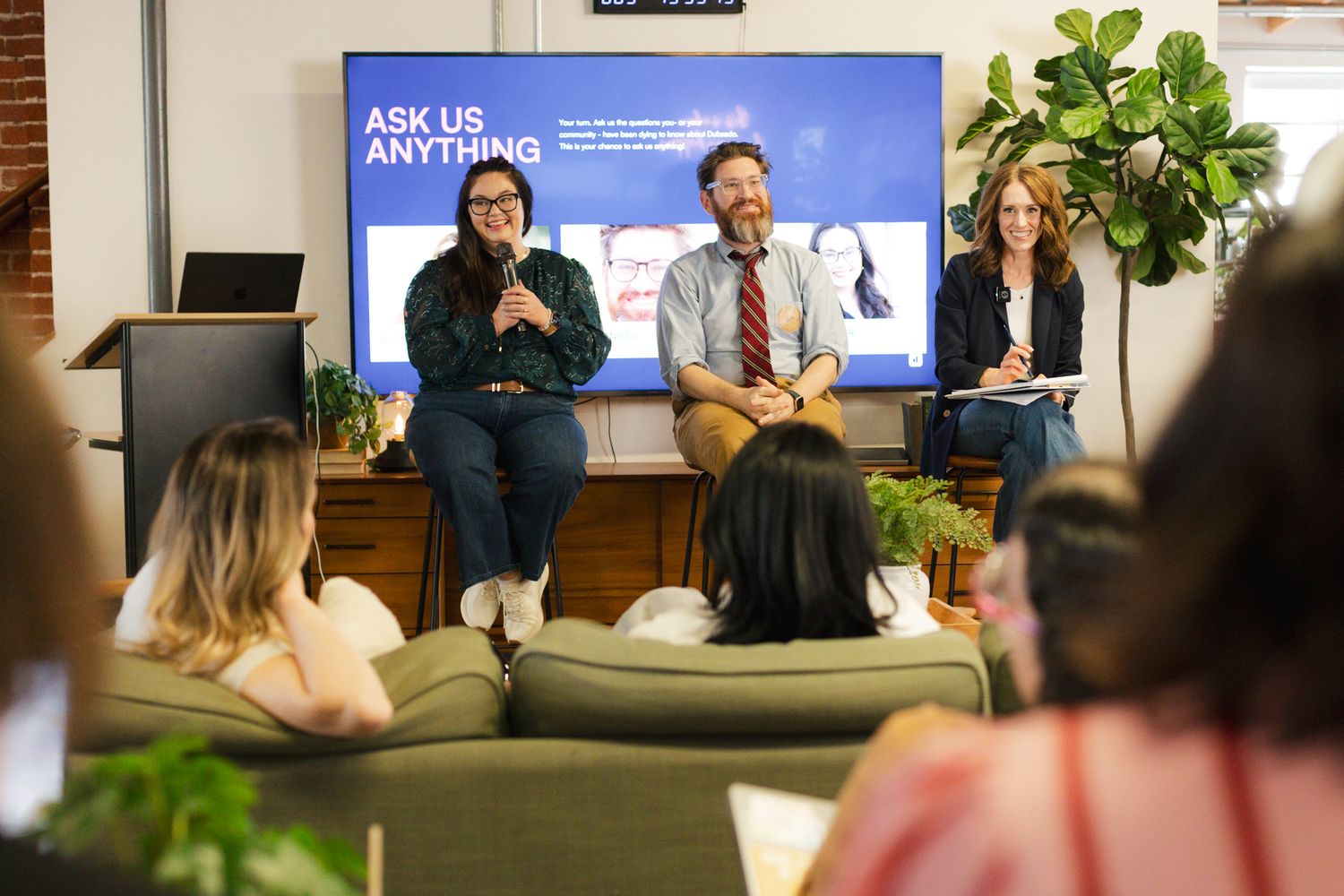 People participate in a business panel discussion in front of a screen displaying 