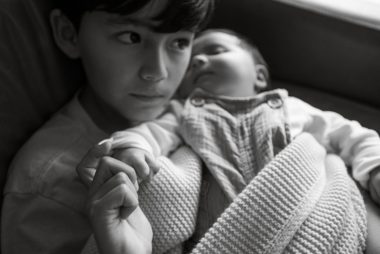 Black and white portrait of newborn sleeping with knit blanket.