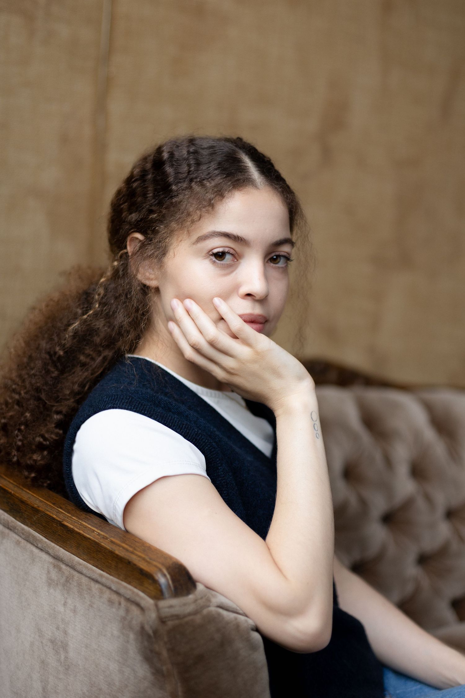 Person with curly hair rests head on hand while lounging.