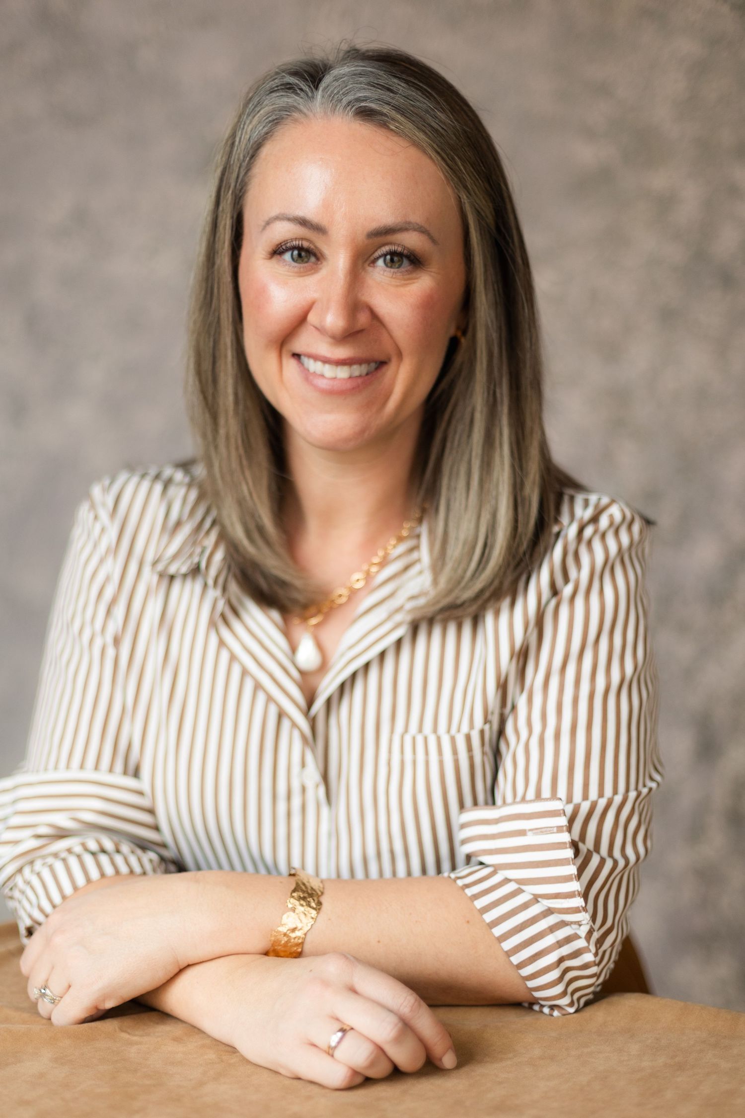 Professional headshot series showing person in striped button-down shirt posing against textured gray backdrop.