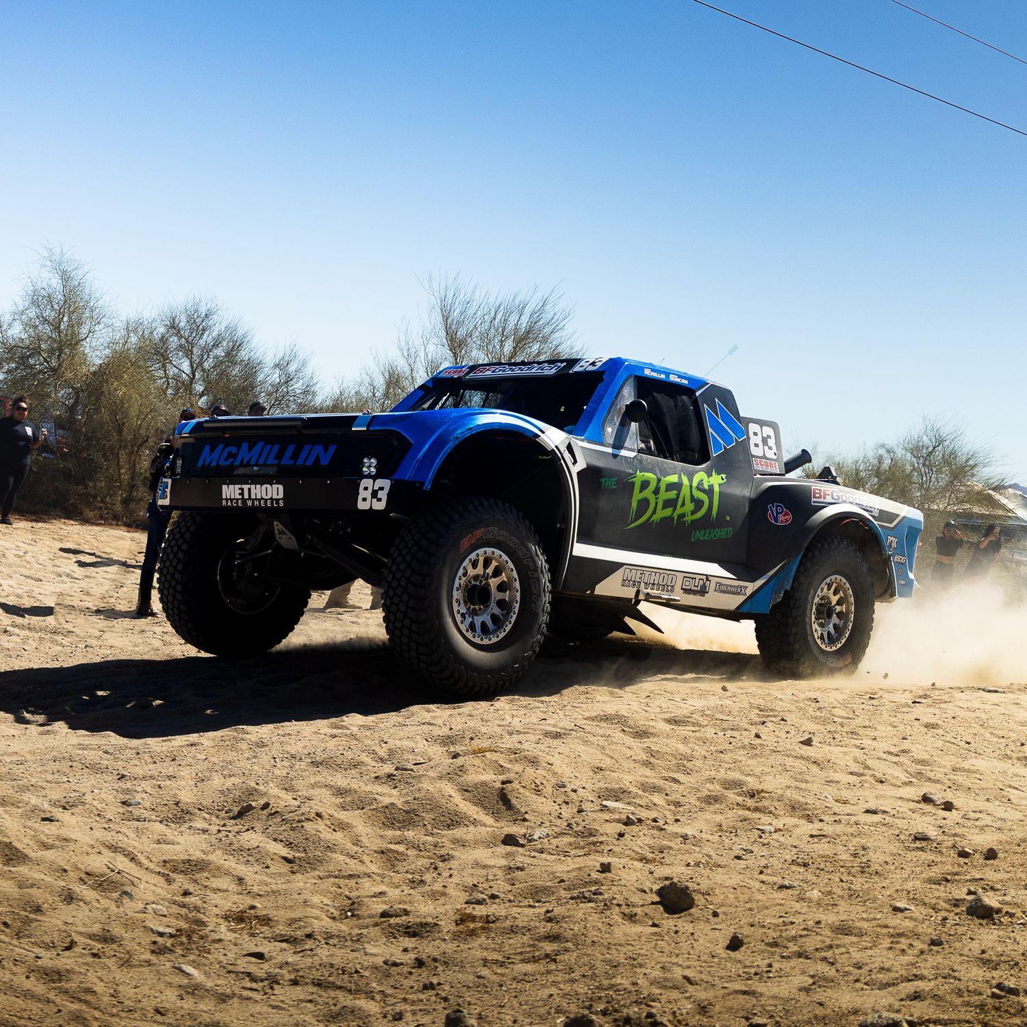 Blue and black Trophy Truck #83 kicking up dust on the San Felipe 250 course during high-speed desert section.