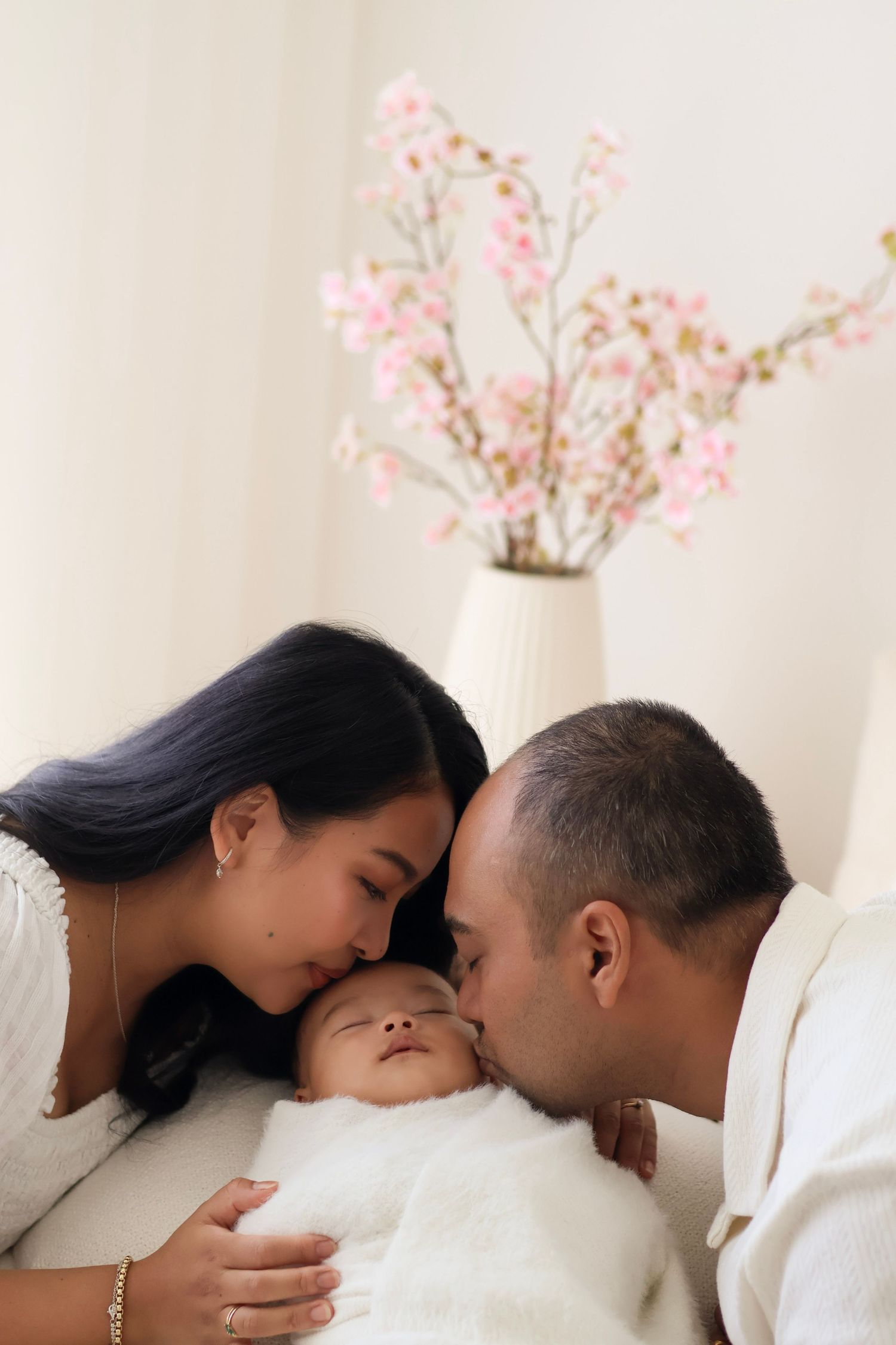 Family photography portrait of couple kissing the baby