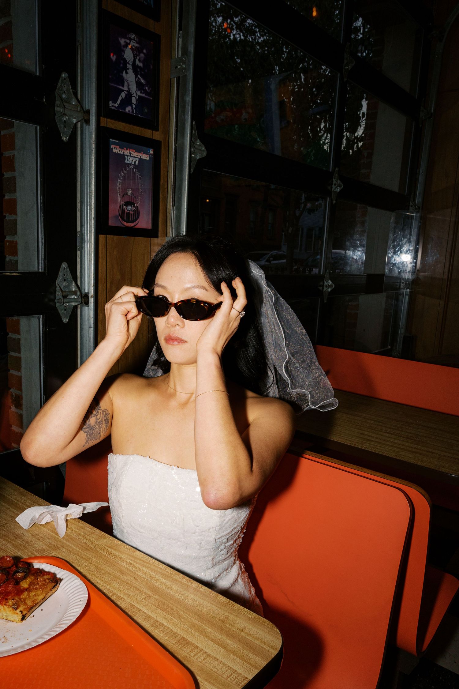 A person in a white dress seated at an orange booth in a dimly lit restaurant.