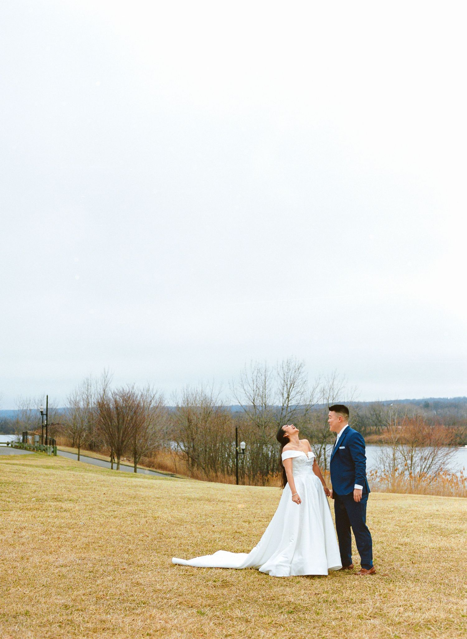 Wedding couple photographed in scenic field with winter landscape backdrop.