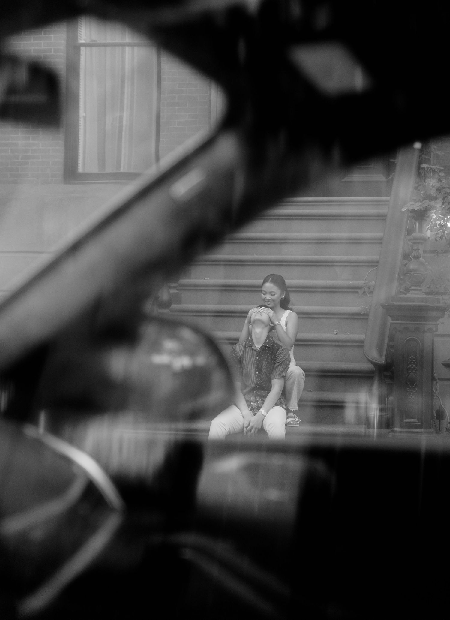 An artistic black and white photo through window frames showing figures in the distance.
