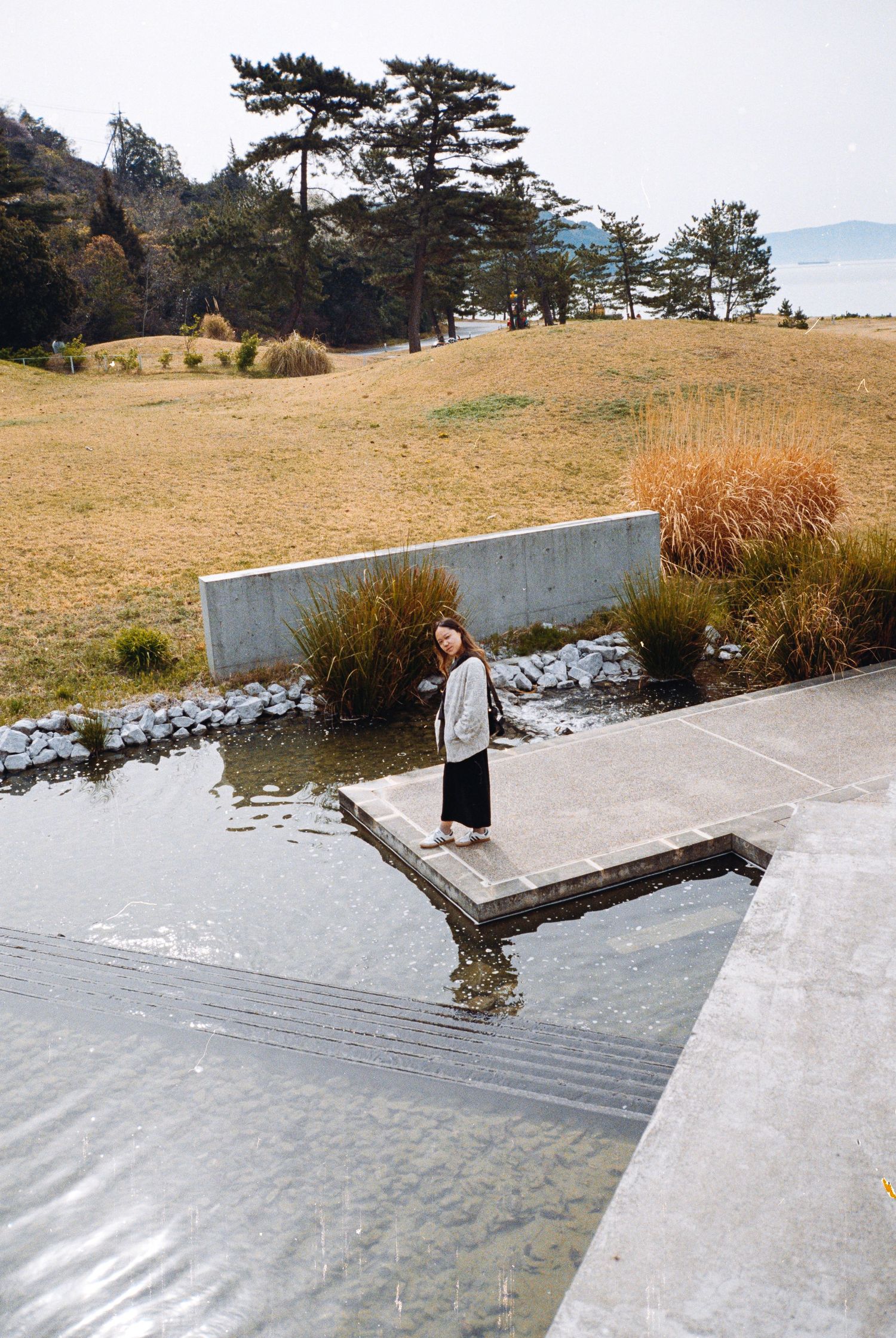 Modern concrete steps descend into a reflective pool with geometric architectural elements.