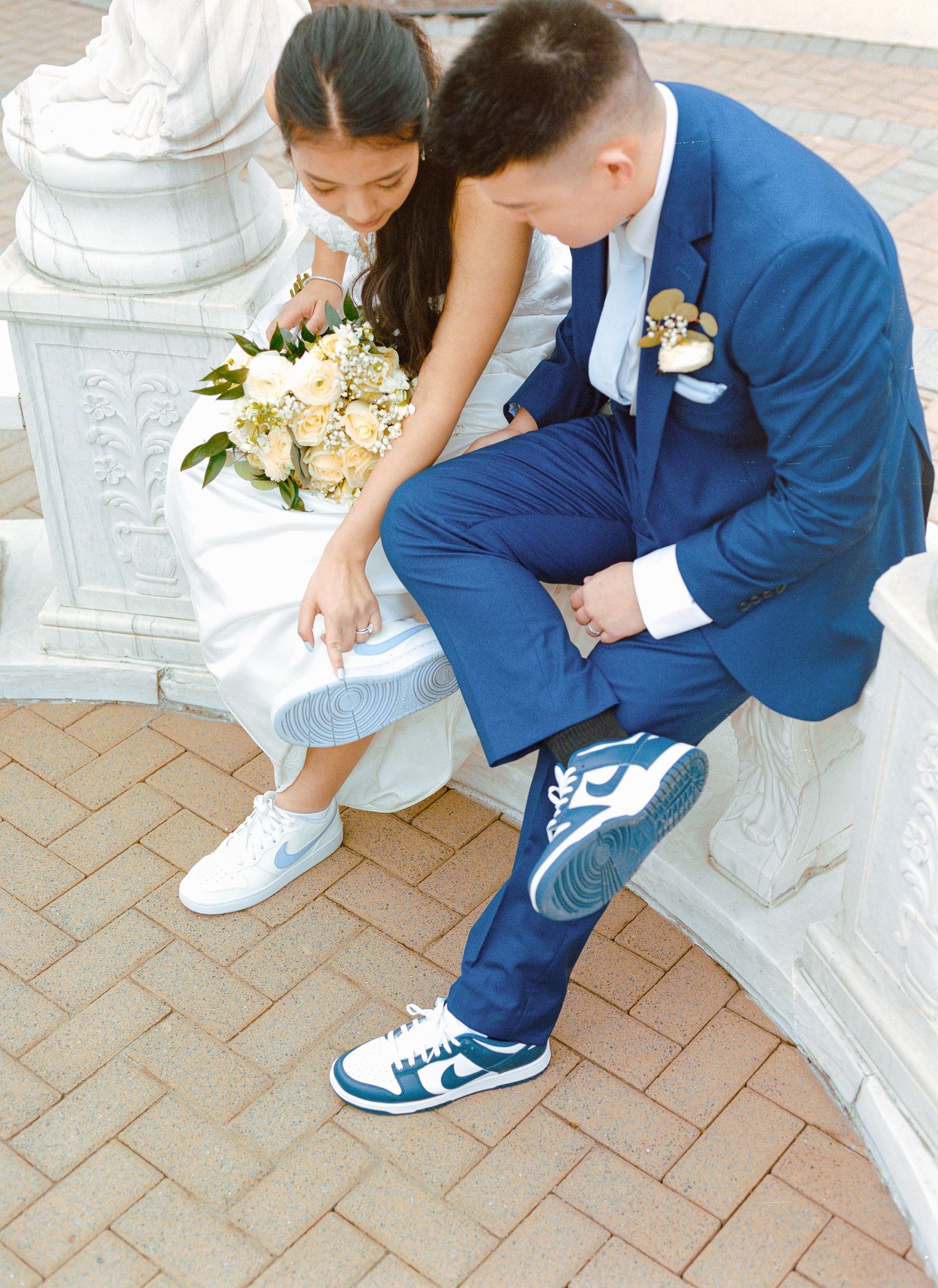 Close-up of bride and groom's matching white sneakers and formal wear.