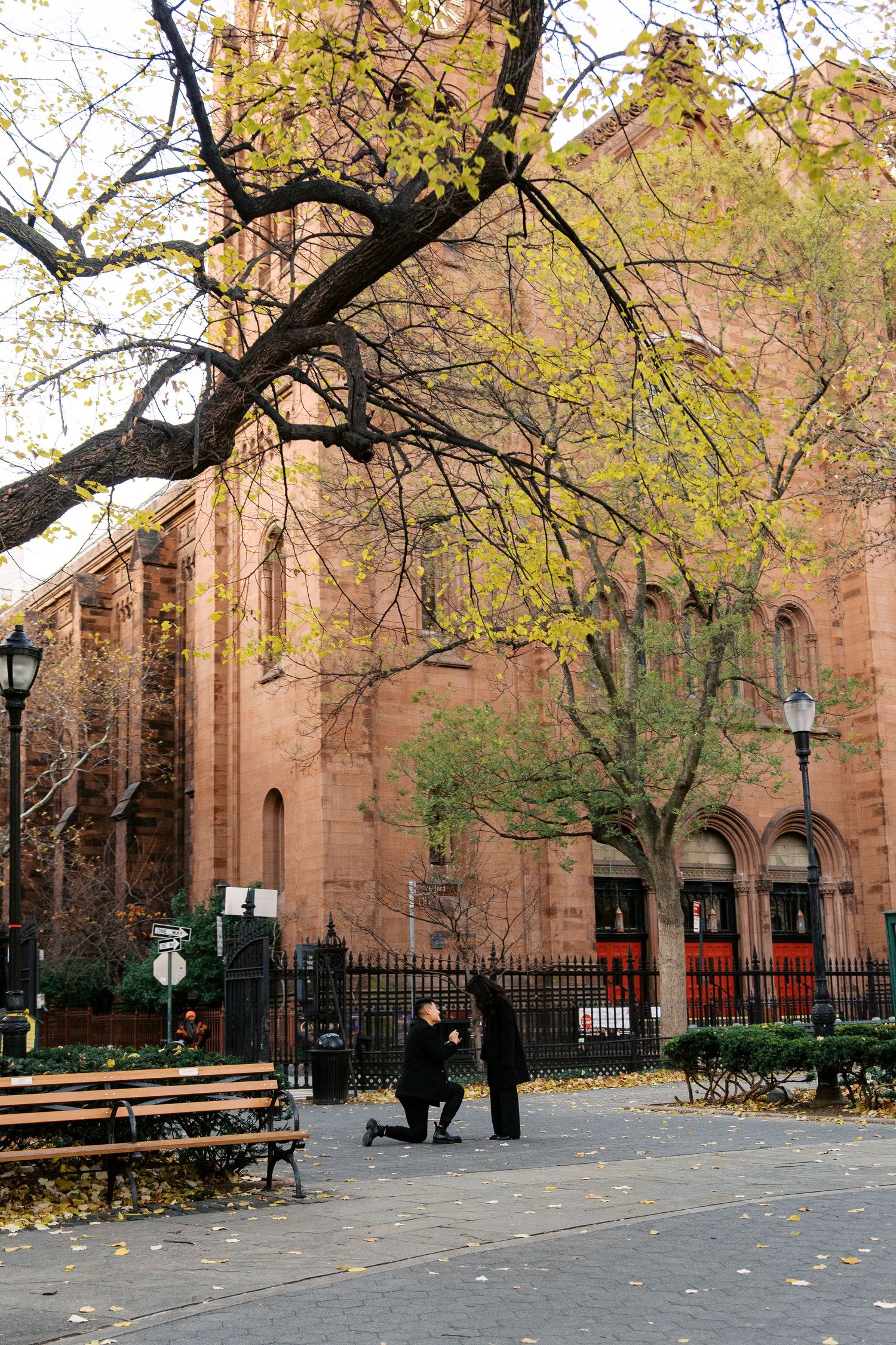 Gothic church exterior with autumn trees and fallen leaves along the pathway.