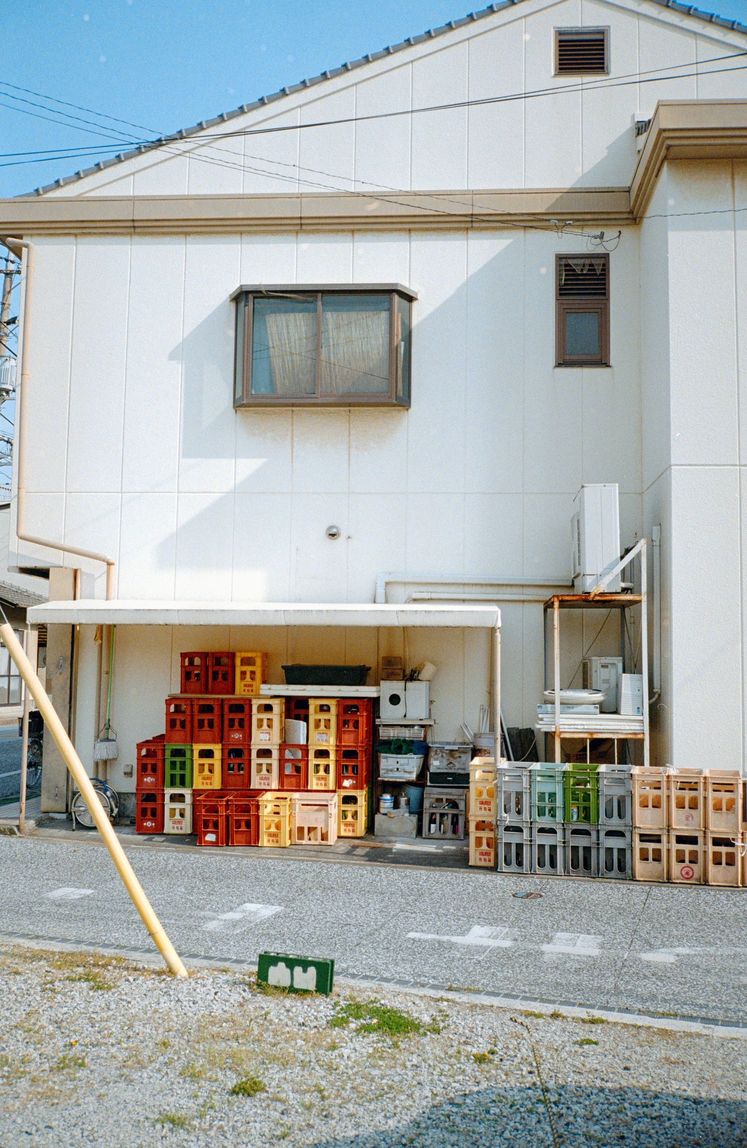 White industrial building exterior with stacked beverage crates arranged along the wall.