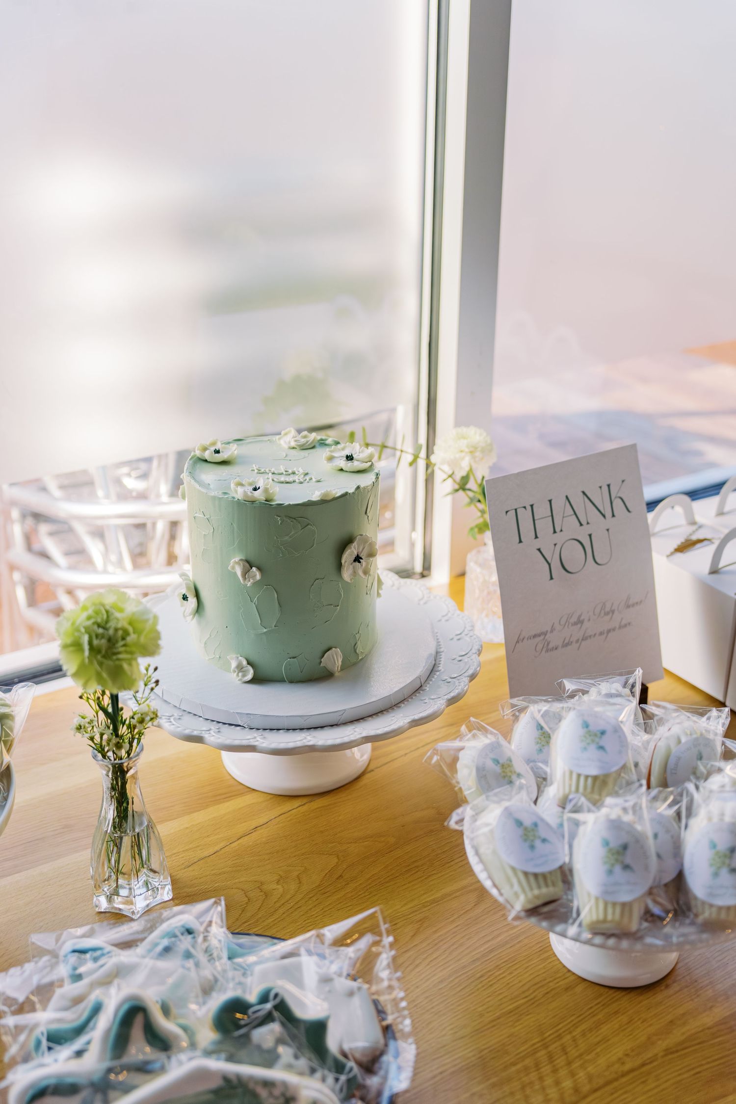 Wedding table decorations featuring pastel cake, thank you cards and floral arrangements.