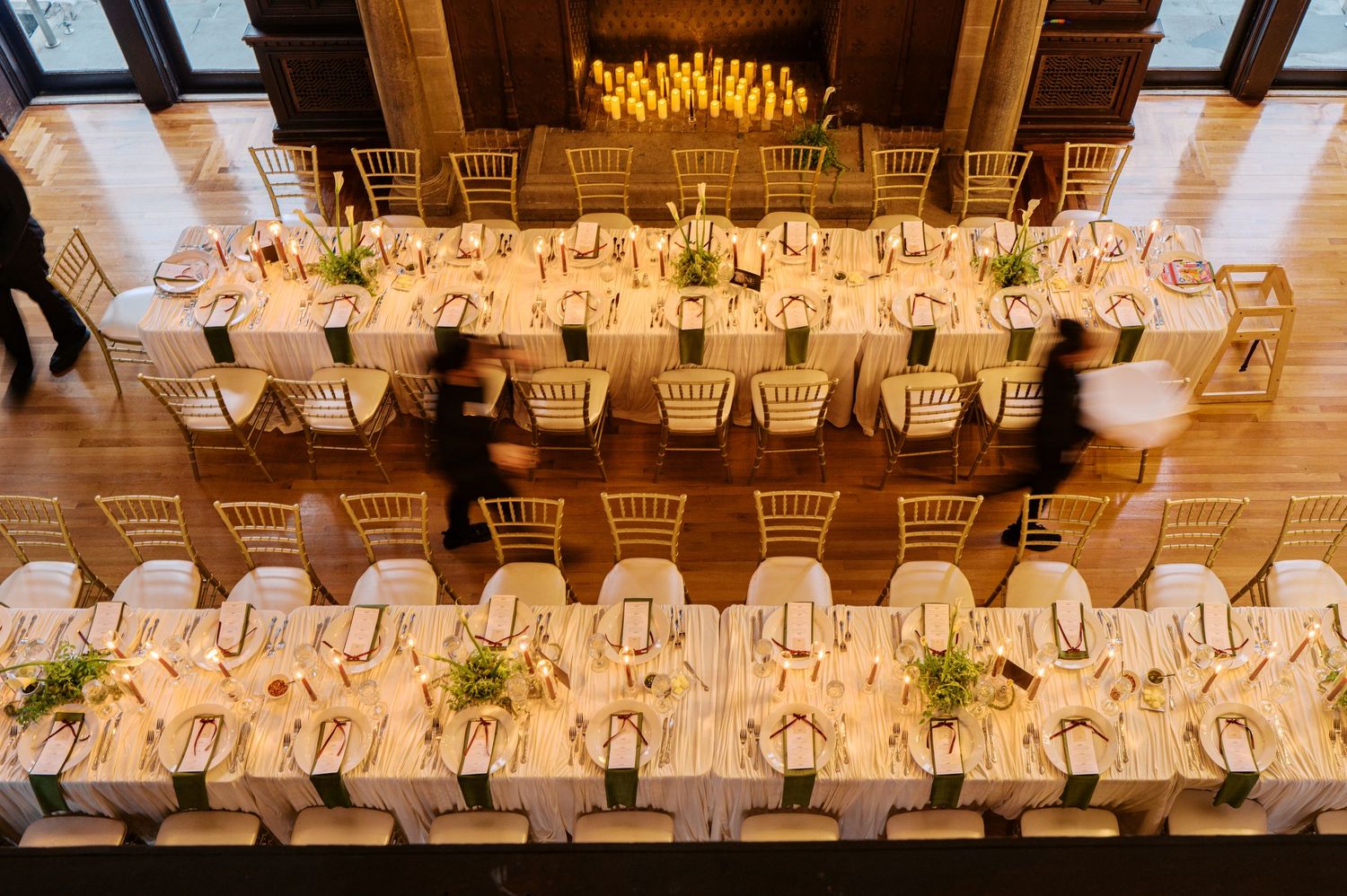Elegant wedding reception venue with white chairs and warm lighting illuminating wooden beams on the ceiling.
