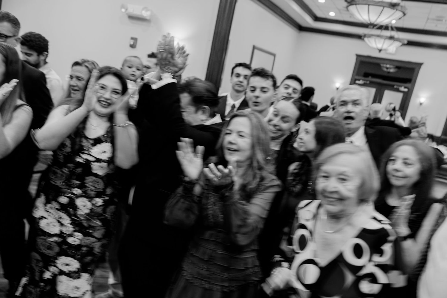 Crowd of wedding guests laughing and dancing together on the dance floor.