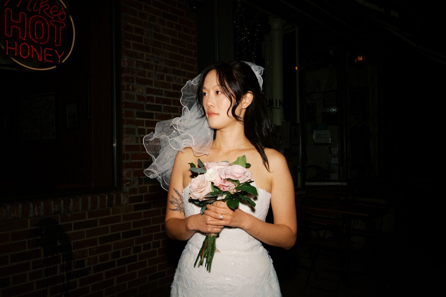 A wedding celebration captured in a dark, moody setting with dramatic lighting and brick walls.