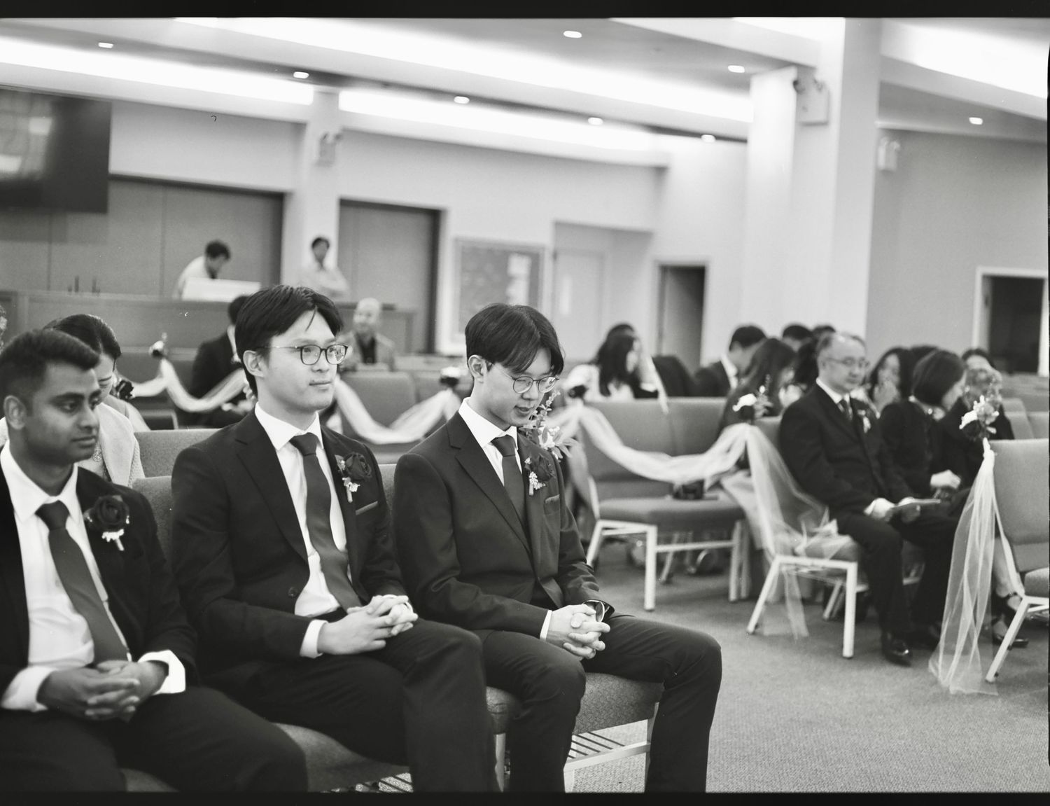 Wide shot of wedding guests seated in rows during an indoor ceremony.