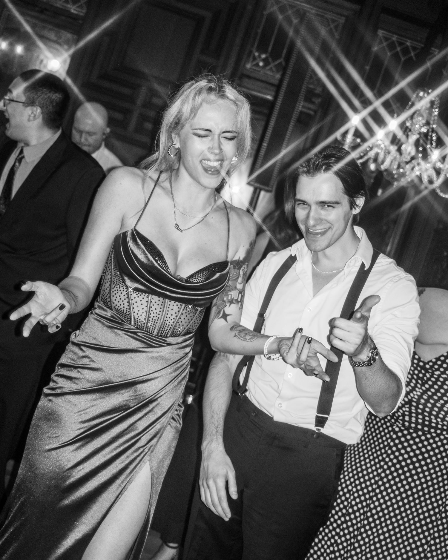 Black and white photo of people dancing and celebrating at a lively party or reception.