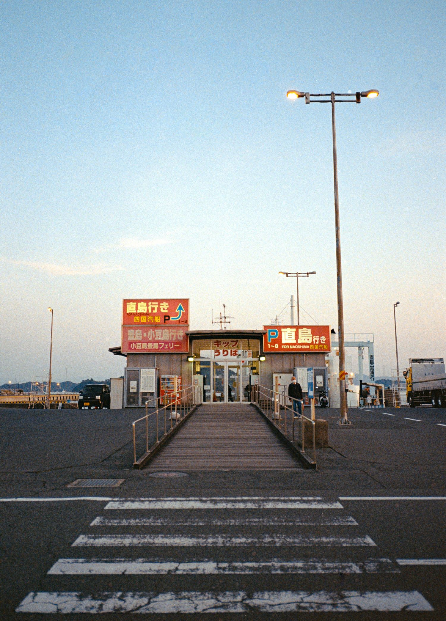 Empty parking lot with convenience store signs at dusk against a fading sky.