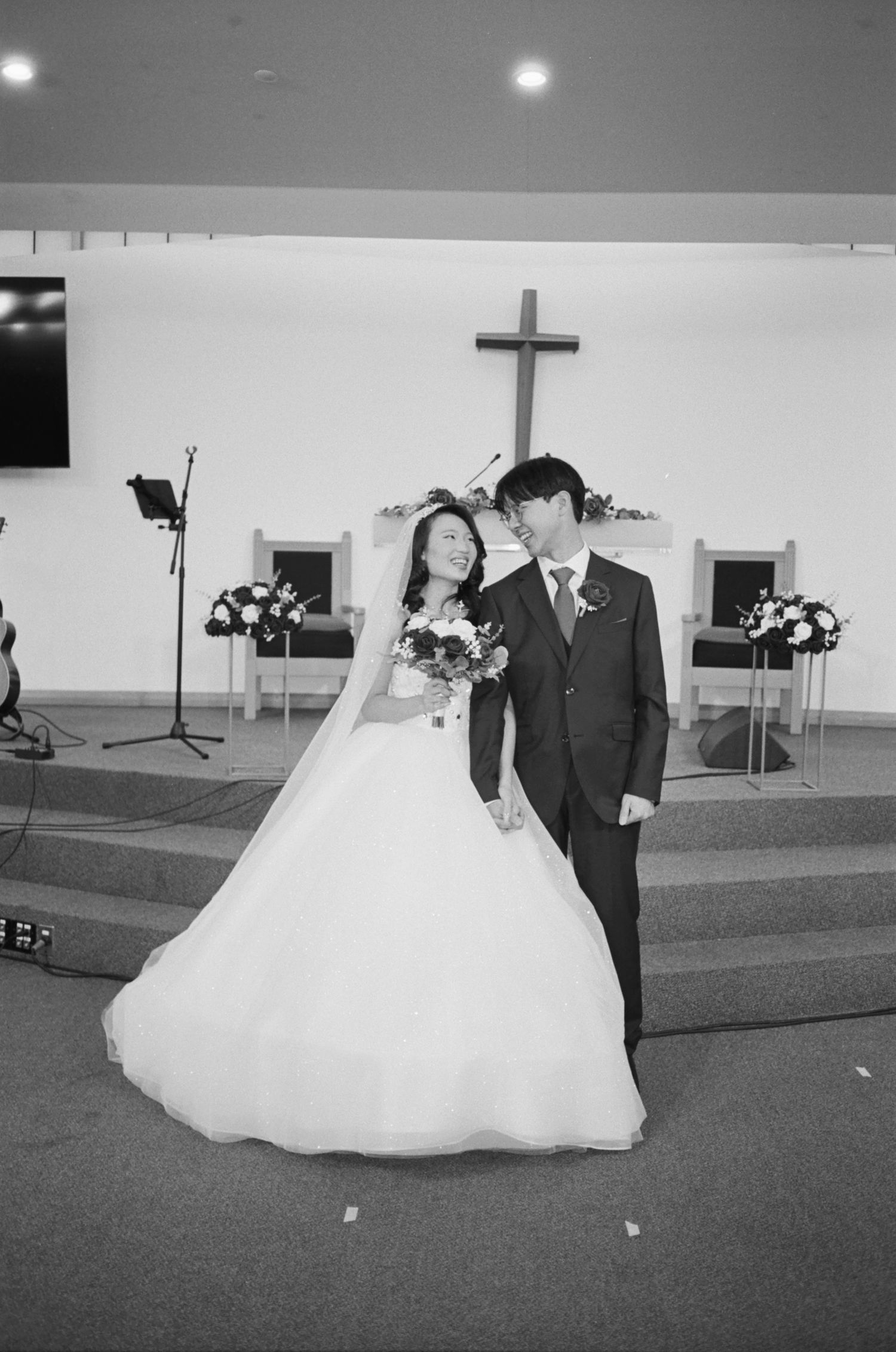 Black and white photos of a wedding couple dancing in a church reception hall.