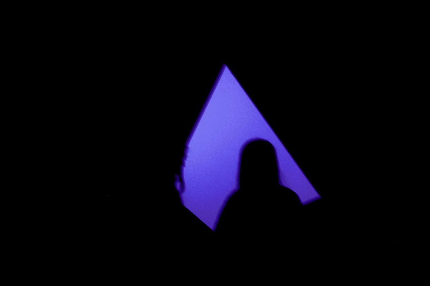 Glowing purple triangular shape illuminated against a dark background.
