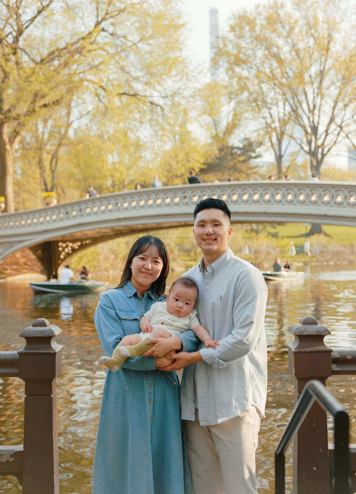 A family portrait at Bow Bridge in Central Park during autumn with fall foliage in the background, captured on film