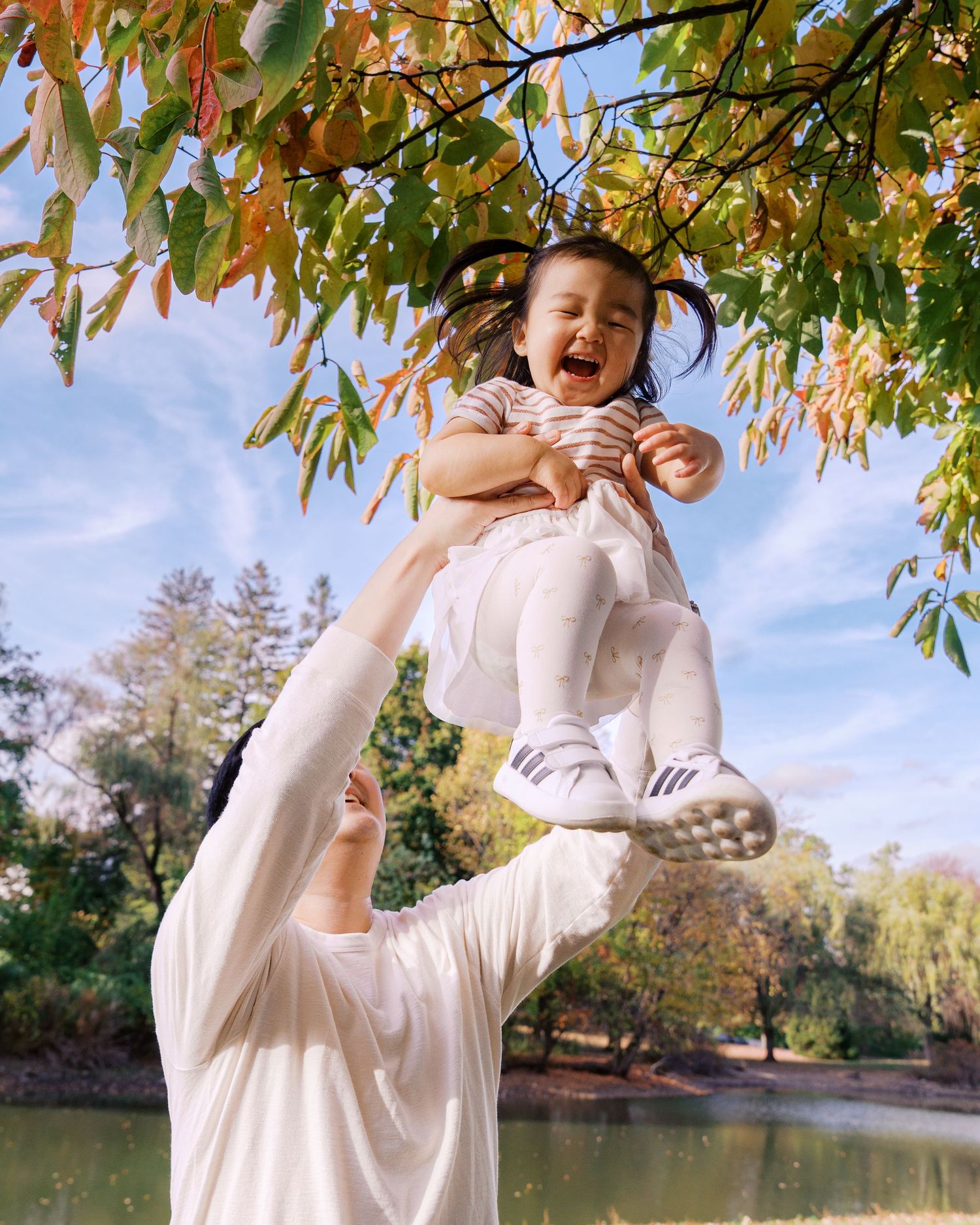 Sequence of joyful movements under autumn trees near a pond.