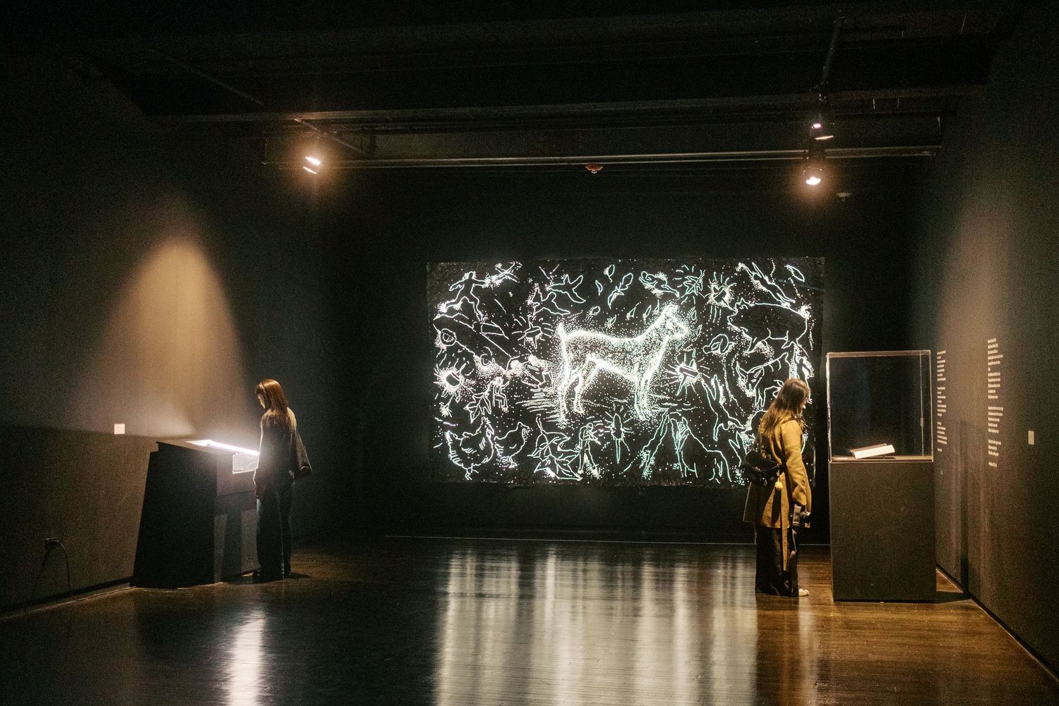 Dark theater stage with dramatic spotlights illuminating performers in an abstract contemporary dance performance.