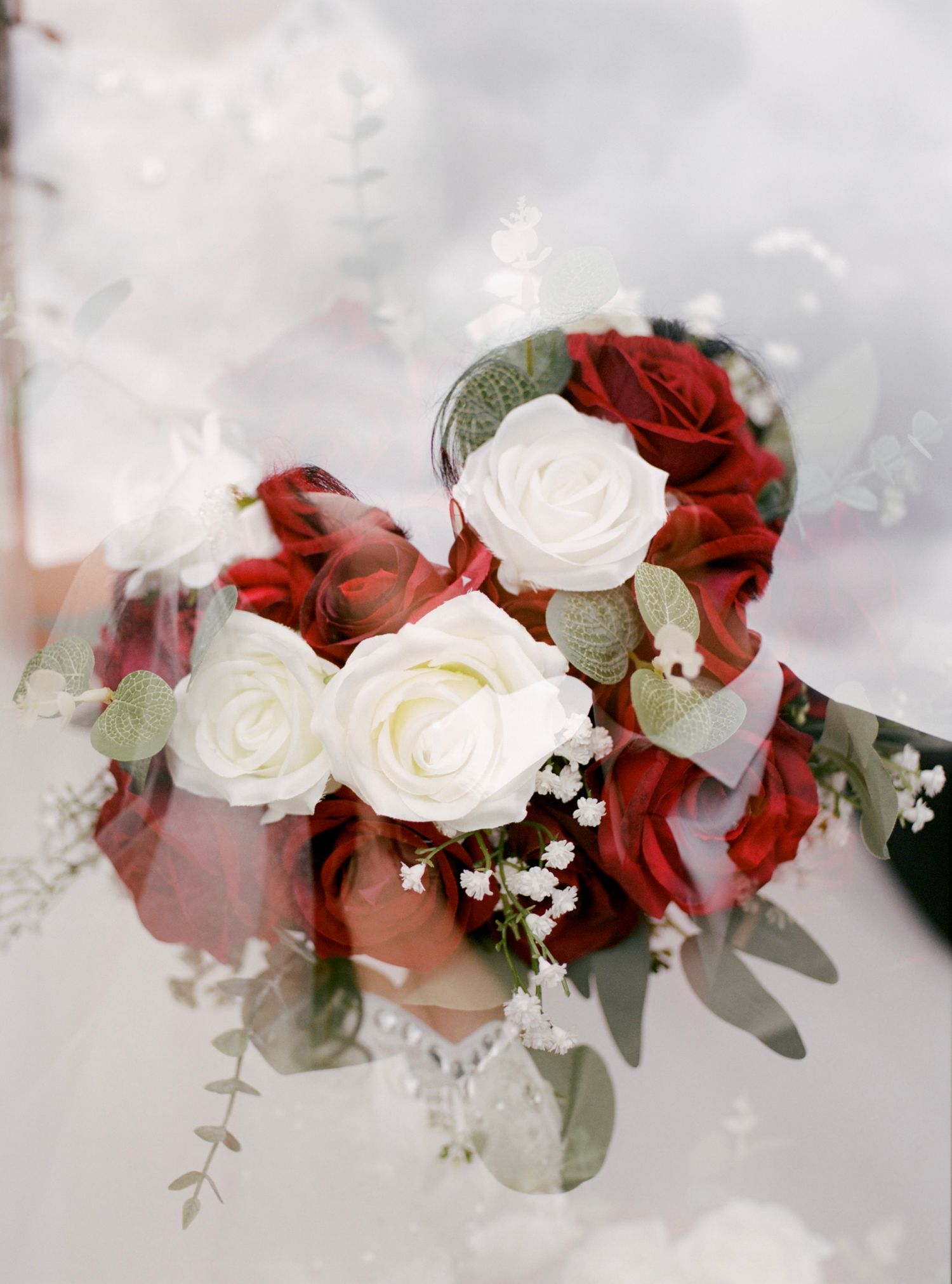 Elegant floral arrangement with red and white roses against a light background.