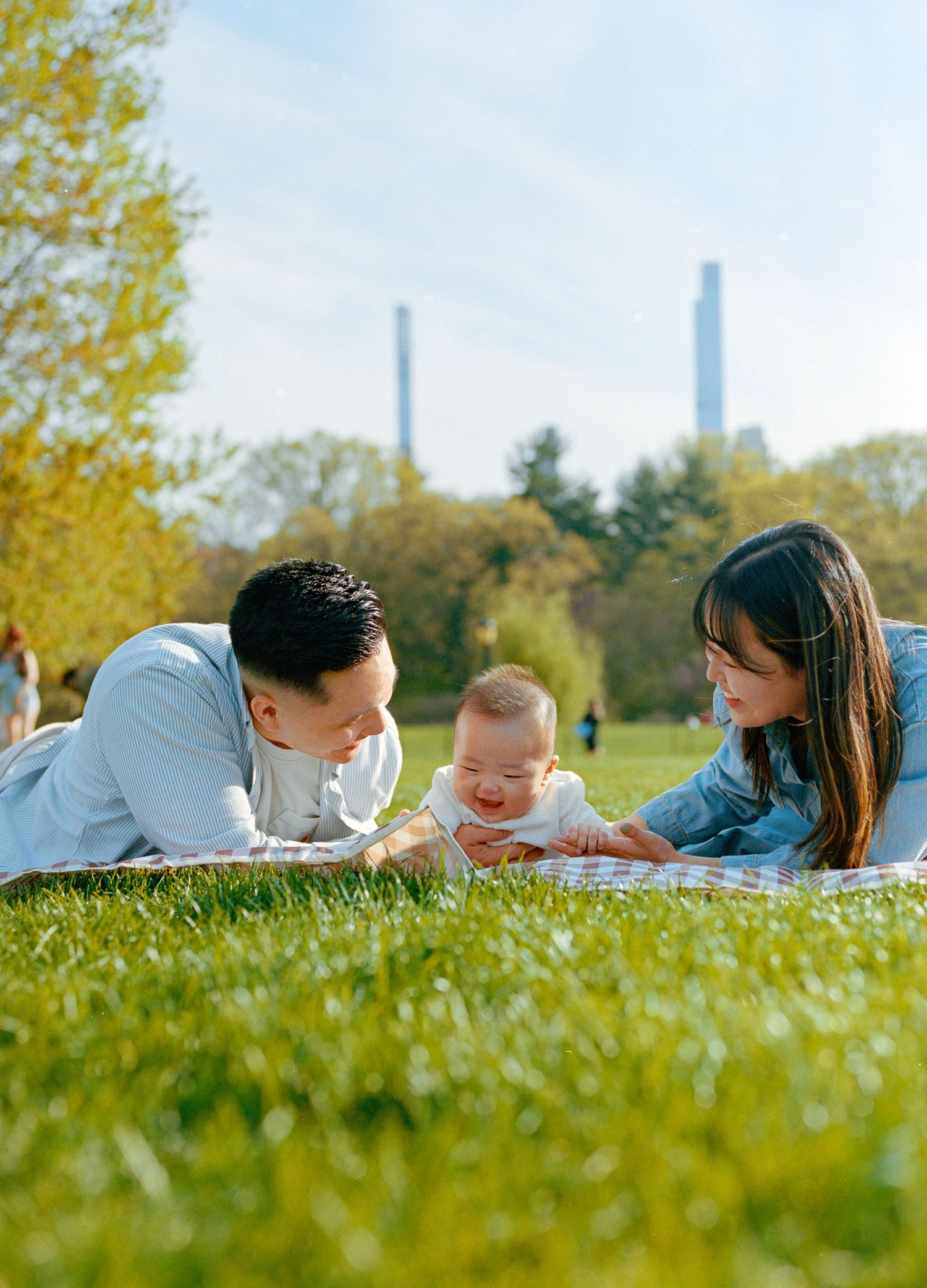 Korean family photography shoot in Spring in Central Park, shot on film with a view of the Manhattan skyline in the background