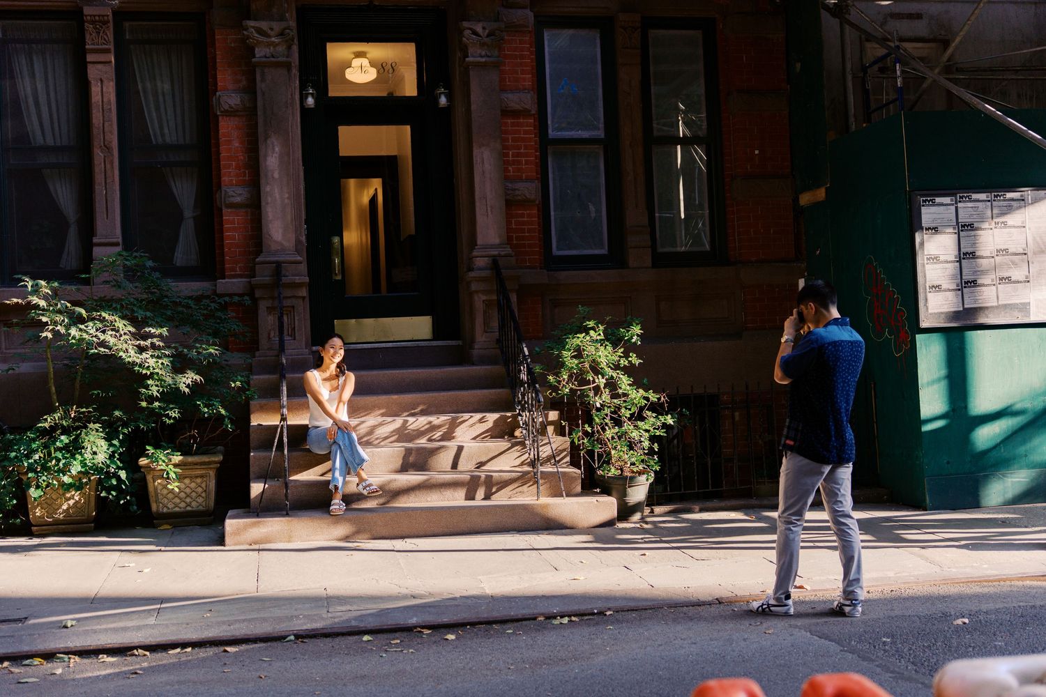 People walking along a charming brick-lined street with classic brownstone buildings.