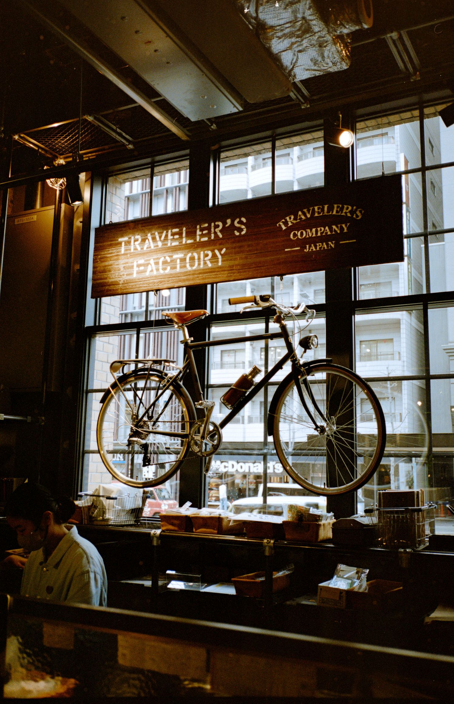 Vintage bicycle hanging from ceiling in dimly lit cafe with 'Traveler's' signage.