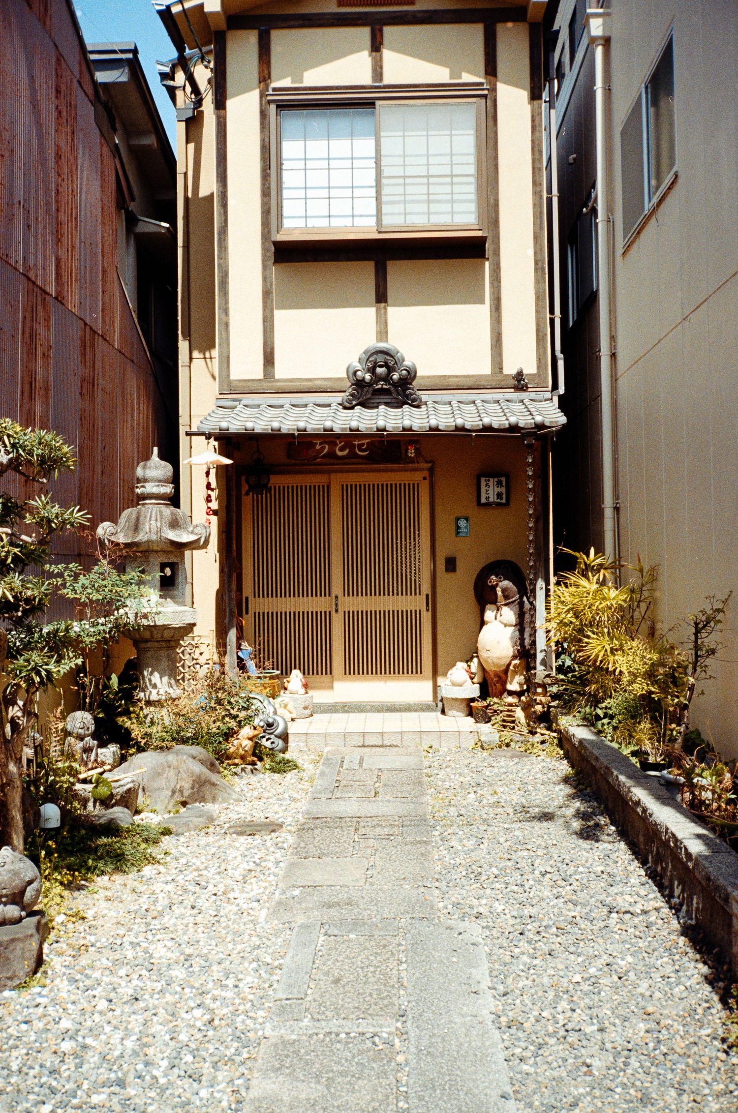 Traditional Japanese house entrance with stone pathway and gravel garden.
