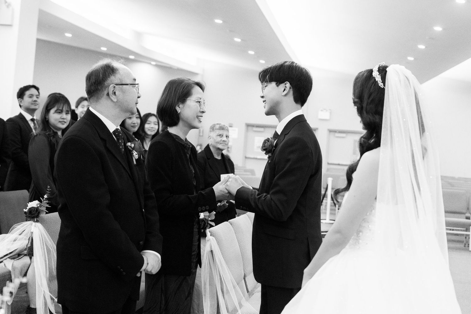 Black and white panoramic view of wedding ceremony guests standing in modern church interior.